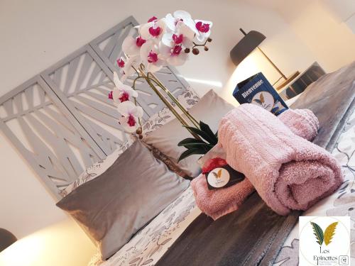 un jarrón de flores sentado en una cama en Les Epinettes chambres d'hôtes, en Crèvecoeur-le-Grand