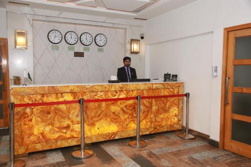 a man sitting at a counter in a room at Lawrence View Hotel, Lahore in Lahore