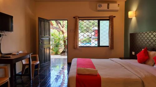 a bedroom with a bed and a desk and a window at Garden Villa in Vagator