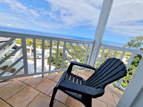 a black chair sitting on a balcony with the ocean at Villa ARC-EN-CIEL in Petite Île