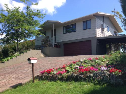 a house with a flower bed in front of it at Baywaterviews in Paihia