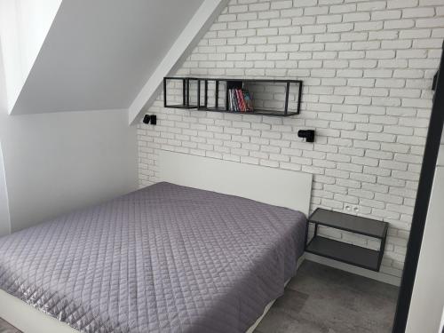 1 dormitorio con 1 cama y pared de ladrillo blanco en Apartmán Pekná Vyhliadka - Vila Vlasta, en Vysoke Tatry - Horny Smokovec