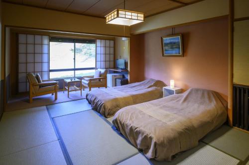a hotel room with two beds and a living room at Takamiya Hotel Jurin in Zao Onsen