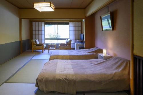 a hotel room with two beds and a living room at Takamiya Hotel Jurin in Zao Onsen