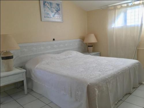 - une chambre blanche avec un lit blanc et 2 tables dans l'établissement Grand bleu-Superbe T2 vue mer & accès plage, au Gosier