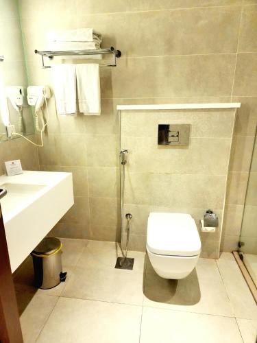 a bathroom with a white toilet and a sink at Best Western Premier Hotel Gulberg Lahore in Lahore