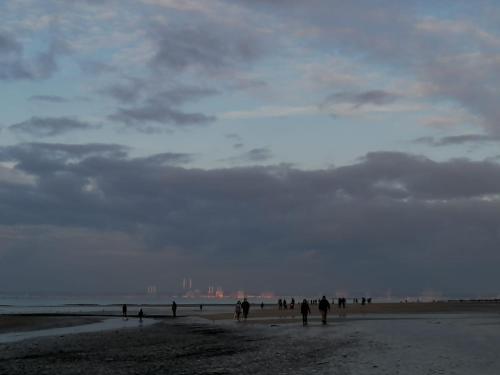 a group of people walking on the beach at La Chambre du 21 in Trouville-sur-Mer