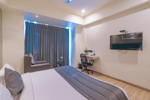 Dormitorio con cama, escritorio y TV en REPUBLIC INN, en Tirupati