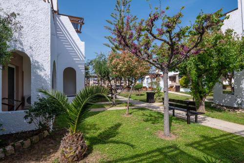 a park with a bench and trees next to a building at Gaia Village in Tigaki