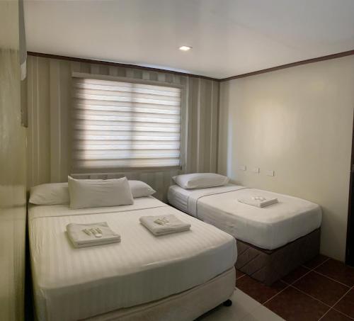 Duas camas num pequeno quarto com uma janela em Anika Island Resort em Ilha de Bantayan