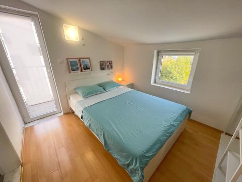 a bedroom with a bed with blue sheets and two windows at Apartmani Tanja in Dramalj