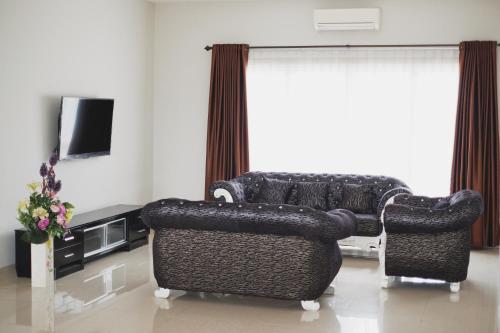 a living room with a black couch and two chairs at Hans Inn Batam in Nagoya