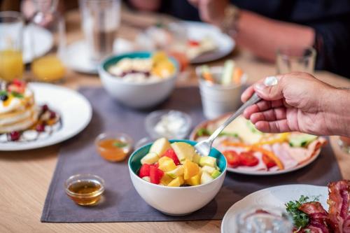 a person eating a bowl of fruit on a table at Aktiv- & Gesundheitsresort das GXUND - Thermeneintritt inklusive in Bad Hofgastein