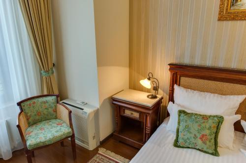 a bedroom with a bed and a chair and a desk at Vila Paris Boutique Hotel in Bucharest