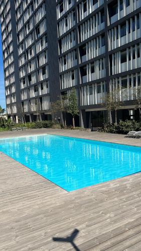 a blue swimming pool in front of a building at Orpheu Deluxe Apt - Parque das Nações in Lisbon