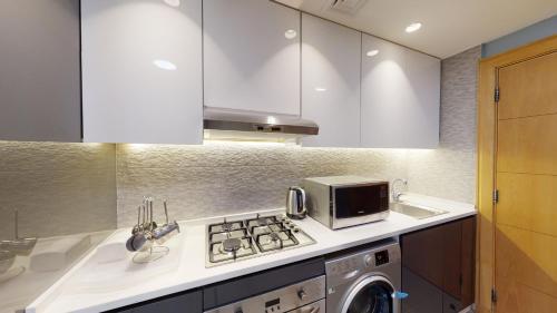 a kitchen with a stove top oven next to a microwave at Al Fares Luxury furnished Apartment-Damac Tower in Amman