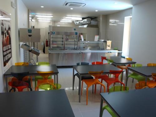 a restaurant with tables and chairs and a kitchen at HI Tavira – Pousada de Juventude in Tavira