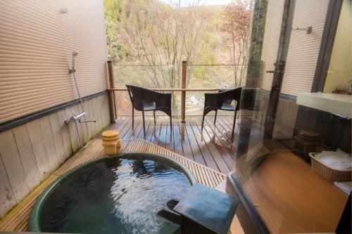 a hot tub on a deck with a table and chairs at Shinshiyo in Hita