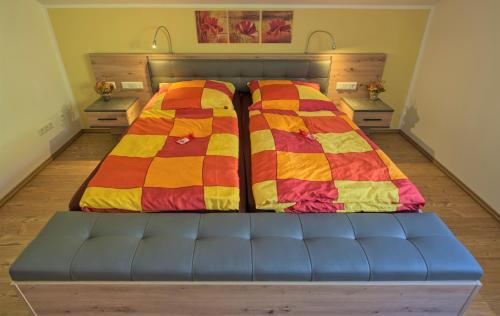 a bed with a blue couch and a colorful blanket at Ferienwohnung Blumäcker Oberbayern in Oberhausen