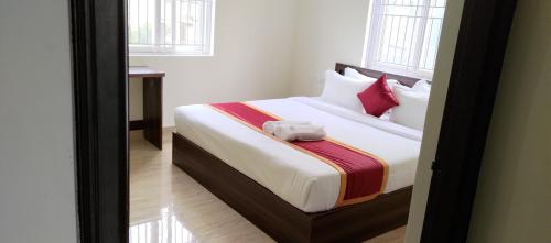 a bedroom with a bed with white sheets and red pillows at Hotel Bangalore Airport Inn, Near kempegowda Airport, Airport Pickup & Drop Available 24X7 in Bengaluru