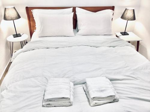 uma cama branca com lençóis e almofadas brancos em Sunny & Bright em Comotini