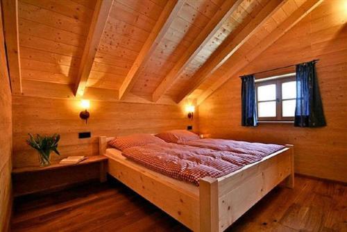 um quarto com uma cama grande num quarto de madeira em Hütten am Waldrand em Altnußberg