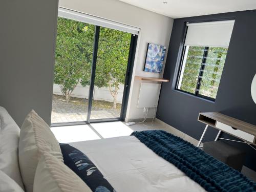 a bedroom with a bed and a large window at Cowrie Cottage Self Catering in Cape Town