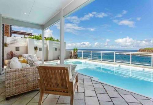 a patio with a swimming pool and a couch at 42 Loves Bay 5 Bedroom Sea cliff View House with Pool in Kiama
