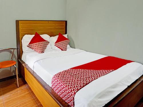 uma cama com almofadas vermelhas e brancas em OYO Life 91814 Griya Asoka Syariah em Bojonegoro