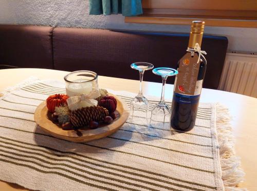 a bottle of wine and a plate of food and wine glasses at Haus Franziska in Kappl