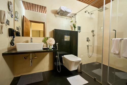 a bathroom with a toilet and a sink and a shower at Visthara Hotel in Bangalore