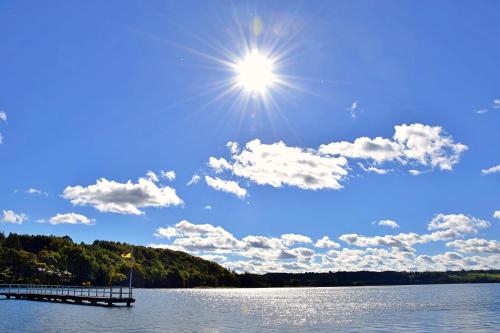 a sun shining over a lake with a dock at Gwiazda Kaszub in Chmielno