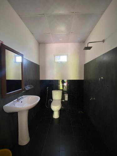 a bathroom with a white sink and a toilet at Elena Garden Resort and Restaurant in Trincomalee