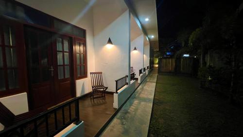 a balcony of a house at night with a chair at Sea Pink Residence in Bentota