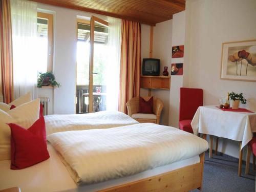 a bedroom with a bed and a table and a window at Pension Einsiedelei in Zwiesel