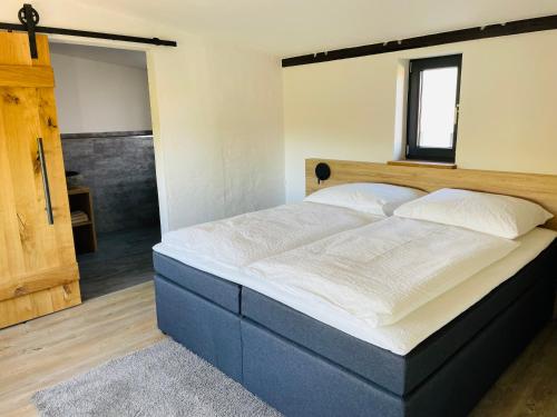 Schlafzimmer mit einem großen Bett mit einem Kopfteil aus Holz in der Unterkunft Deichgraf „Die Elbpension“ in Dornburg