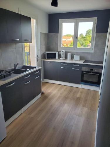 uma cozinha com armários pretos e piso em madeira em Appartement moderne et équipé em LʼIsle-Jourdain