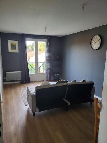 1 dormitorio con 1 cama y reloj en la pared en Appartement moderne et équipé, en LʼIsle-Jourdain