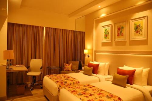 a hotel room with two beds and a desk at Efcee Sarovar Premiere Bhavnagar in Bhavnagar