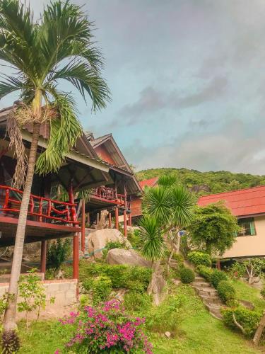 a resort with a palm tree and a building at Tanouy Garden in Baan Khai