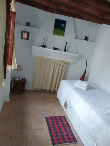a bedroom with two beds and a window and a rug at Casa Balcón in Granada