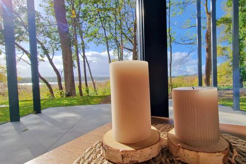 two white candles sitting on a table in front of a window at Gwiazda Kaszub in Chmielno