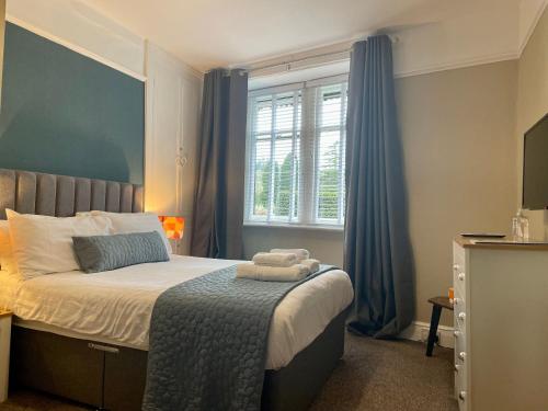 a bedroom with a bed with blue curtains and a window at Lacet House in Ambleside