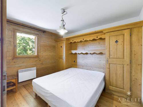 Cette chambre en bois comprend un lit blanc. dans l'établissement Appartement cosy, 2 pièces, terrasse, parking, proche centre et remontées, Montvalezan - FR-1-398-520, à La Rosière