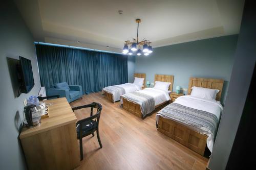 a hotel room with two beds and a desk and a table at Hotel InnDigo in Kutaisi in Kutaisi