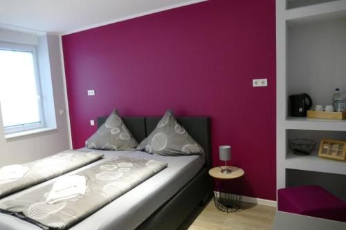 a bedroom with a purple wall and a bed at Pension Sölde UG in Dortmund