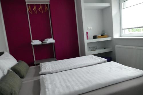 two beds in a room with purple walls and a window at Pension Sölde UG in Dortmund