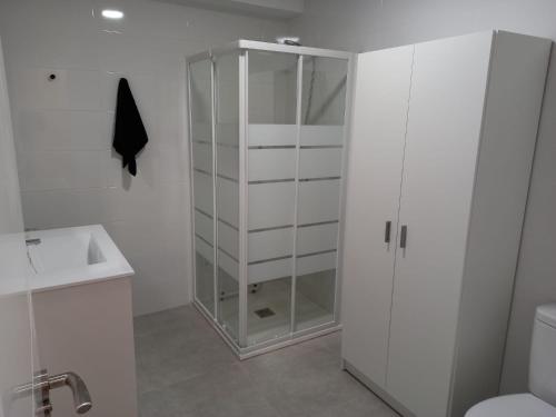 a white bathroom with a glass cabinet and a toilet at la vall in Caserío Abdet