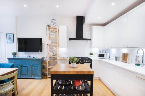una cucina con armadi bianchi e isola blu di Meadowbank Residence 3bed free parking a Edimburgo