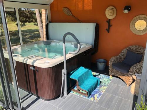 a hot tub sitting inside of a house with a chair at Maison au cœur des étangs de Sologne avec SPA , Domaine de Sainte-Marie in Ardon